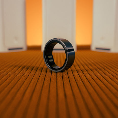 close up view of gray Lotus Ring on a brown textured surface and 3 white Switch covers upright in the background.