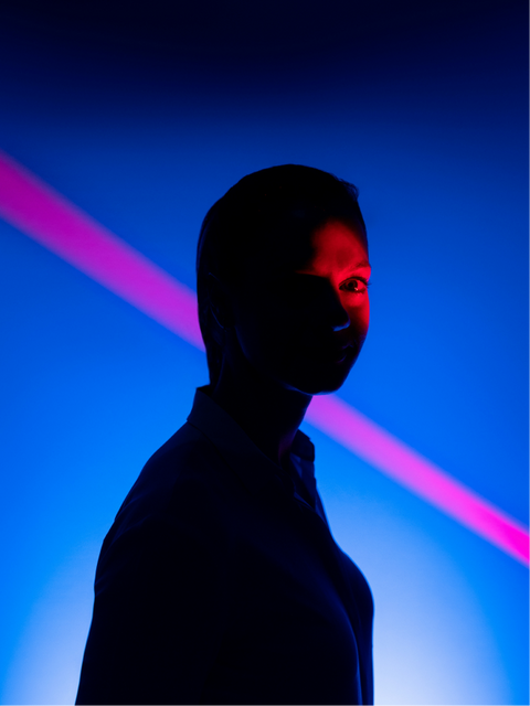 A person figure illuminated by neon blue and red lights