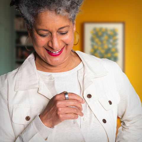 Older adult woman smiling down at Lotus Ring on index finger