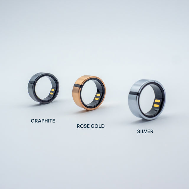 Three Lotus rings in graphite, rose gold, and silver on a light gray background