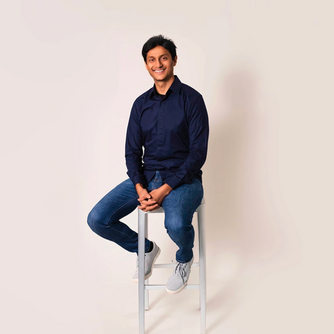 Dhaval Patel, an Indian man, smiling while sitting on a stool.